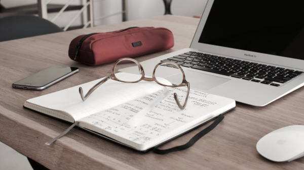 Laptop i notatnik leżące na drewnianym biurku